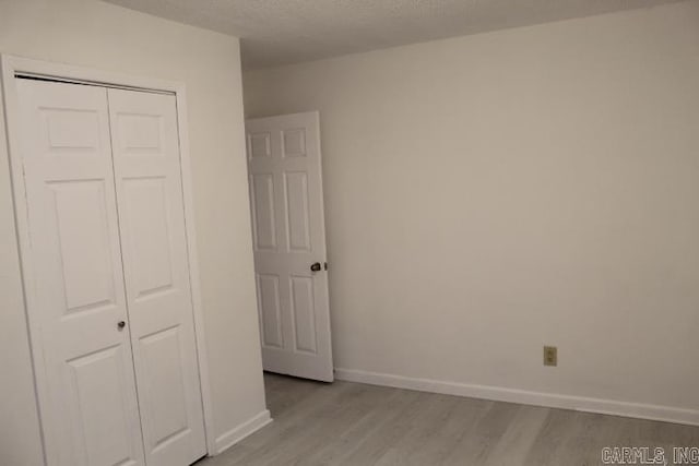 unfurnished bedroom with a closet, a textured ceiling, and light hardwood / wood-style flooring