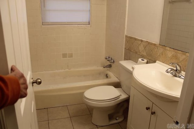 full bathroom with tile patterned floors, vanity, tiled shower / bath combo, tile walls, and toilet