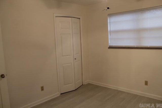 unfurnished bedroom with light wood-type flooring and a closet