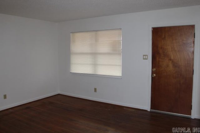 spare room with dark wood-type flooring and a textured ceiling