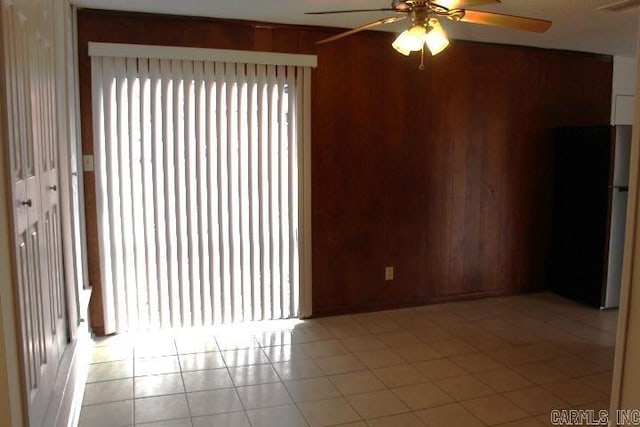 tiled empty room with ceiling fan and wood walls