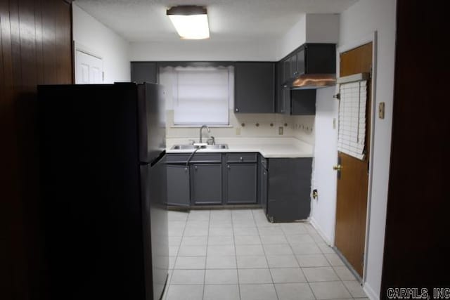 kitchen with sink, tasteful backsplash, gray cabinets, black refrigerator, and light tile patterned floors