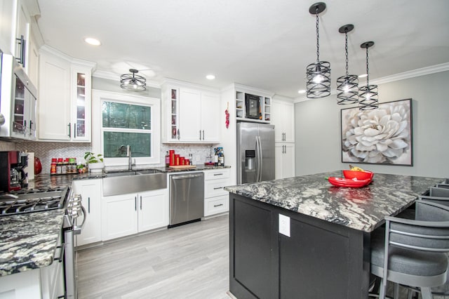 kitchen with sink, white cabinets, stainless steel appliances, and decorative light fixtures