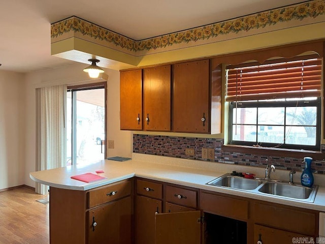 kitchen with tasteful backsplash, kitchen peninsula, sink, and plenty of natural light