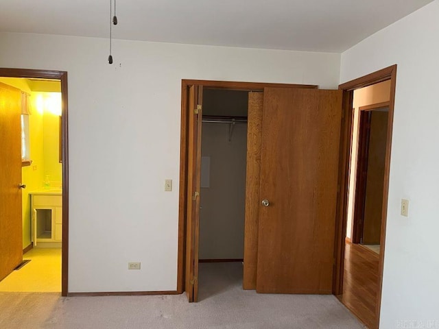 unfurnished bedroom with ensuite bath, light carpet, and a closet