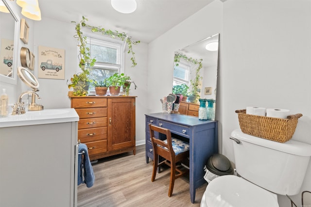 bathroom with hardwood / wood-style floors, toilet, a wealth of natural light, and sink