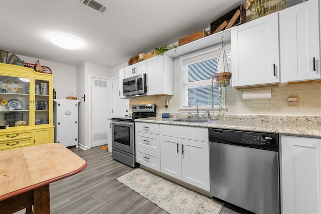 kitchen featuring decorative backsplash, sink, white cabinets, and appliances with stainless steel finishes