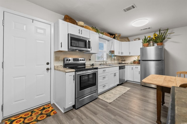 kitchen with decorative backsplash, white cabinetry, sink, and appliances with stainless steel finishes