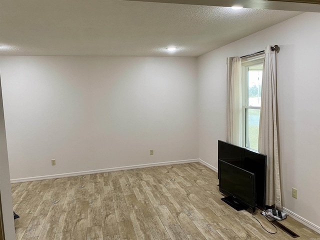 spare room with a textured ceiling and light hardwood / wood-style flooring