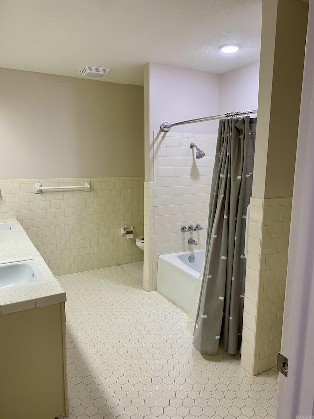 full bathroom with shower / bath combo, tile patterned floors, toilet, vanity, and tile walls