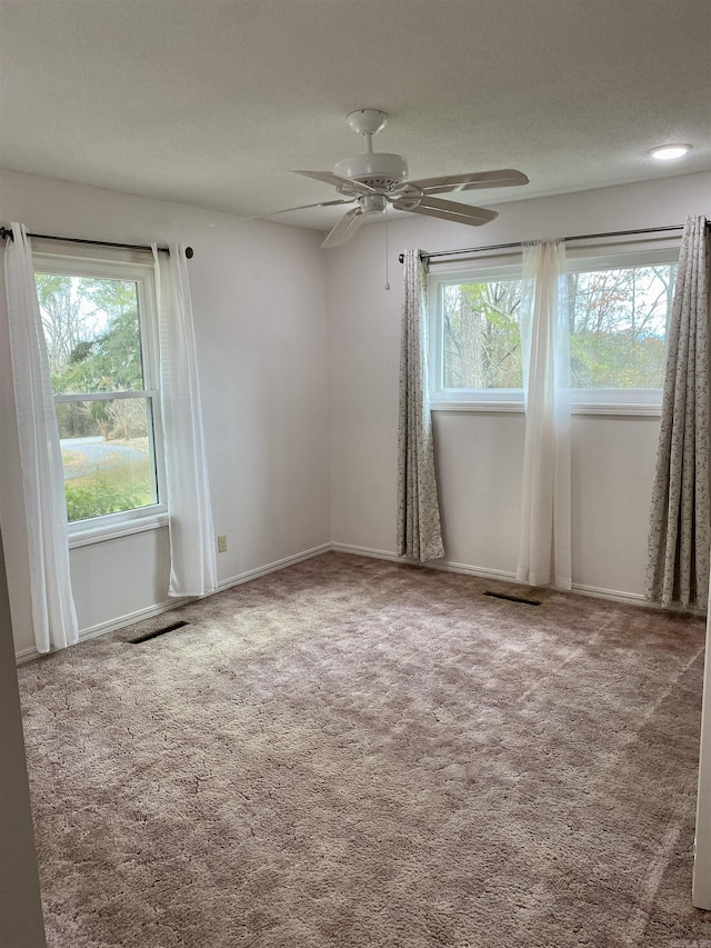 carpeted spare room with ceiling fan and plenty of natural light