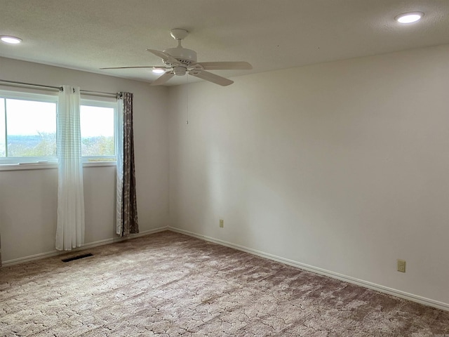 spare room featuring light carpet, ceiling fan, and a textured ceiling