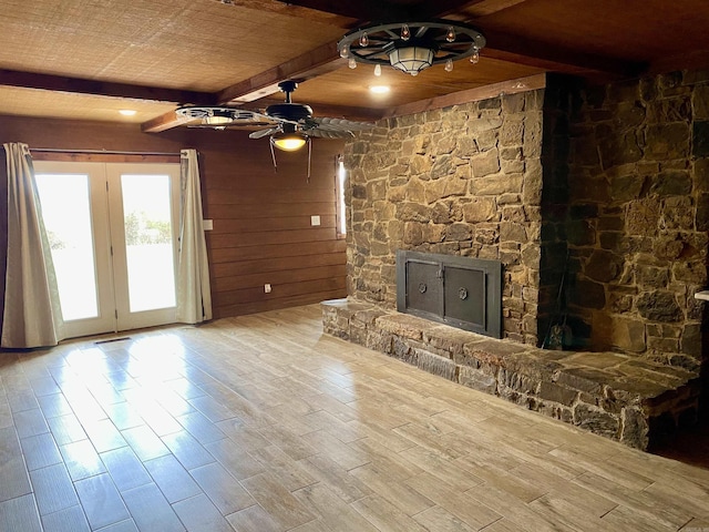 unfurnished living room featuring beam ceiling, ceiling fan, a fireplace, wood ceiling, and light wood-type flooring