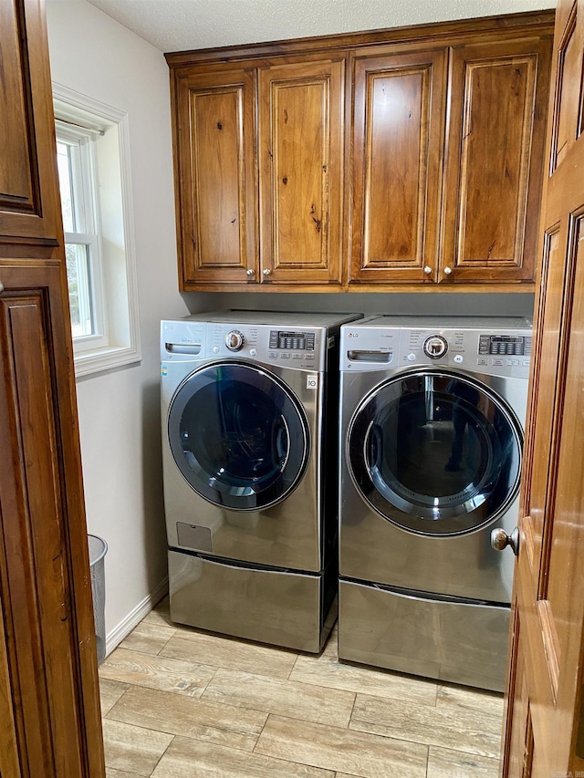 clothes washing area featuring cabinets and separate washer and dryer