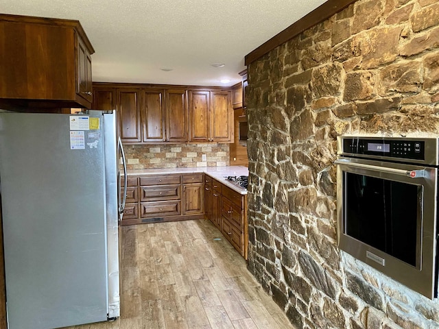 kitchen with a textured ceiling, light hardwood / wood-style floors, and stainless steel appliances