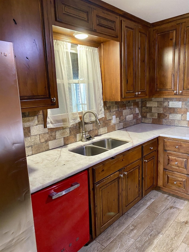 kitchen featuring decorative backsplash, light hardwood / wood-style floors, light stone counters, and sink