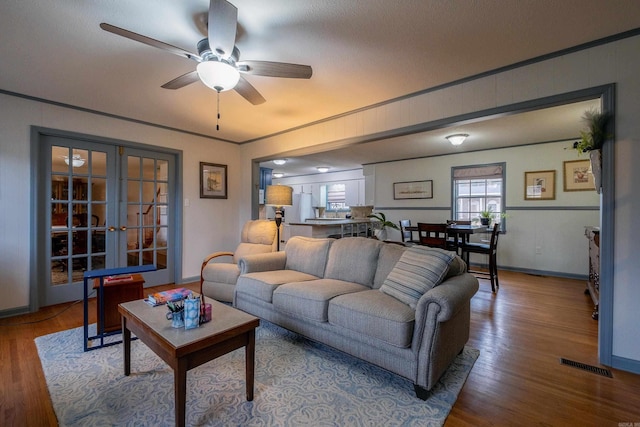 living room with hardwood / wood-style flooring, ceiling fan, crown molding, and french doors