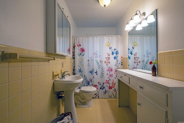 bathroom with a textured ceiling, tile walls, and toilet