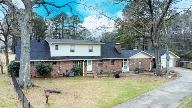 rear view of property featuring cooling unit, a yard, an outbuilding, and a garage