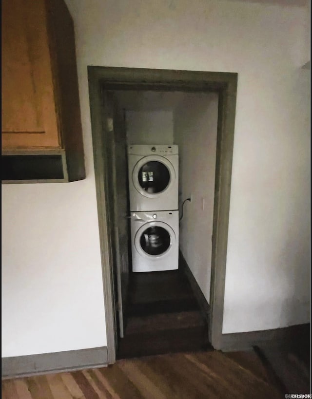 laundry room with stacked washer / dryer and dark hardwood / wood-style flooring