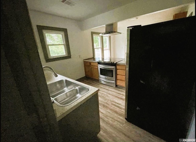 kitchen with black fridge, electric stove, sink, light wood-type flooring, and extractor fan