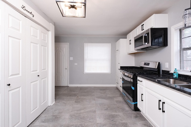 kitchen with white cabinets, sink, appliances with stainless steel finishes, and dark stone counters