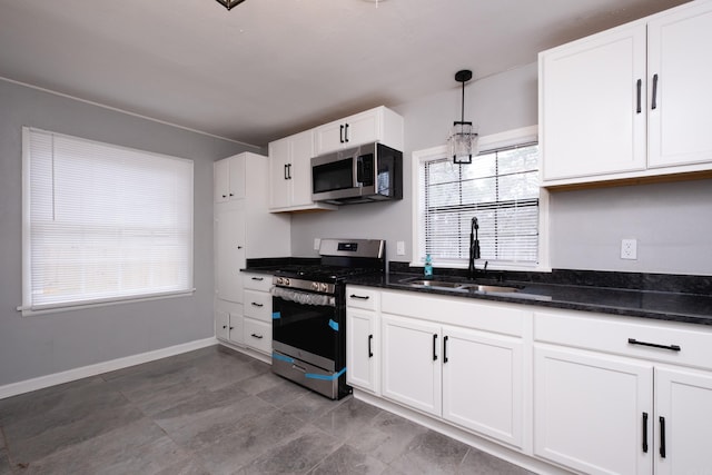 kitchen featuring stainless steel appliances, a healthy amount of sunlight, sink, white cabinets, and hanging light fixtures