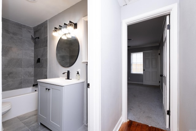 full bathroom with hardwood / wood-style floors, vanity, tiled shower / bath combo, and toilet