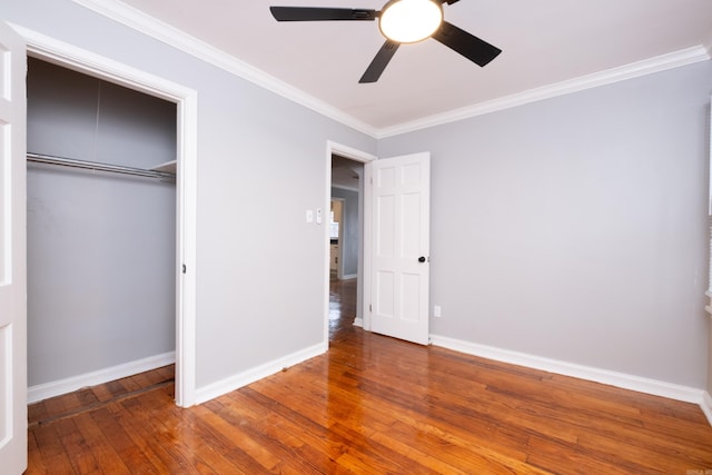 unfurnished bedroom featuring wood-type flooring, a closet, ceiling fan, and crown molding