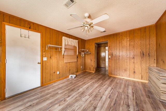 unfurnished bedroom featuring ceiling fan, a closet, wood walls, and a textured ceiling