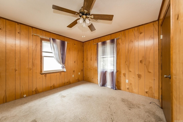 empty room featuring carpet, ceiling fan, and wood walls