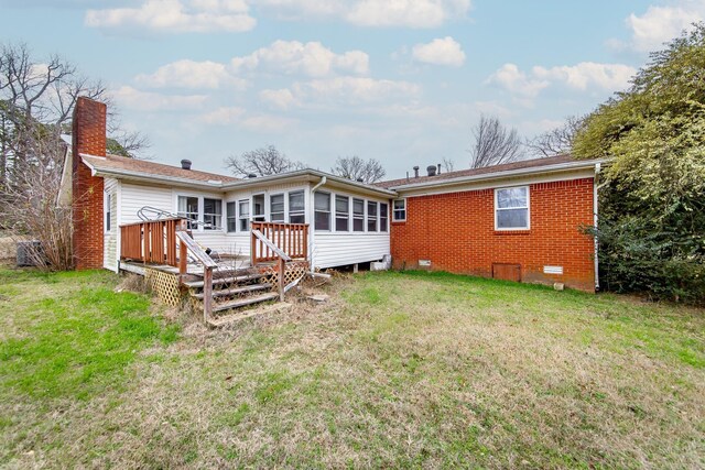 rear view of property featuring a sunroom, a yard, and a wooden deck