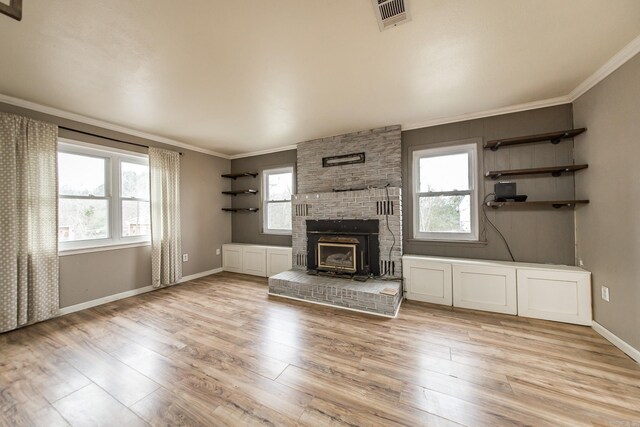 unfurnished living room featuring a wood stove, crown molding, and light hardwood / wood-style flooring