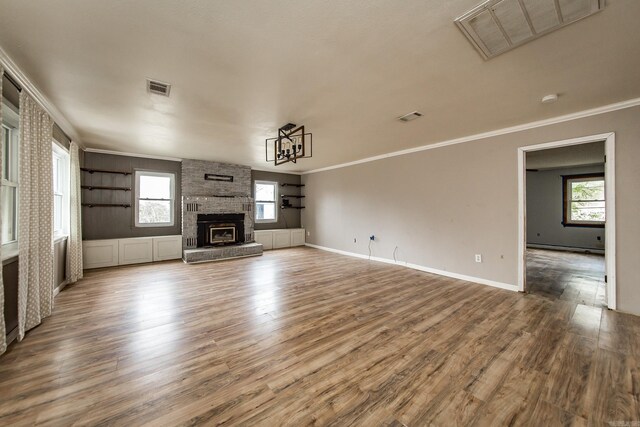 unfurnished living room with hardwood / wood-style floors, plenty of natural light, crown molding, and a fireplace