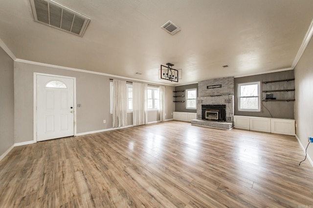 unfurnished living room with light hardwood / wood-style floors, a stone fireplace, and crown molding