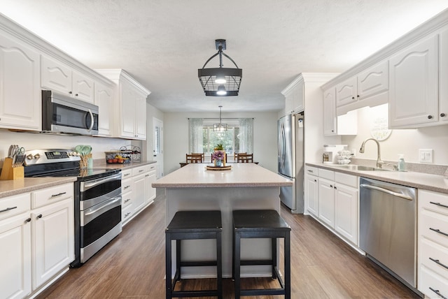 kitchen with white cabinets, decorative light fixtures, sink, and stainless steel appliances