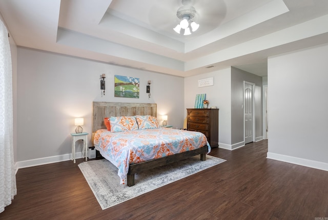 bedroom featuring ceiling fan, a raised ceiling, and dark wood-type flooring