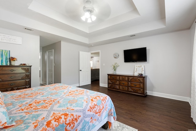 bedroom with ceiling fan, dark hardwood / wood-style flooring, and a raised ceiling