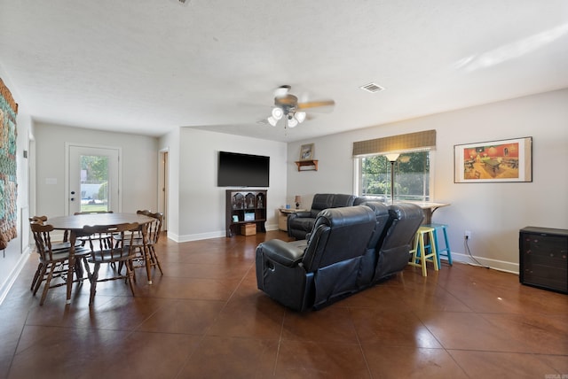 living room with ceiling fan and dark tile patterned flooring