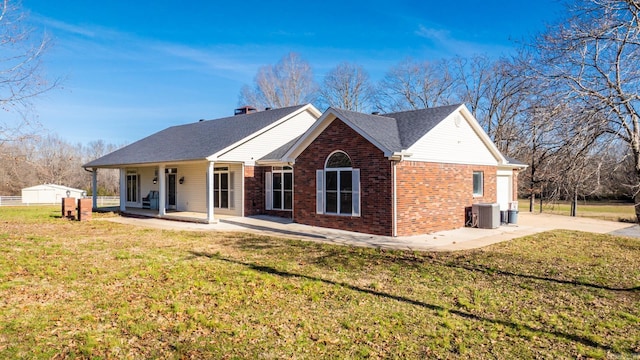 rear view of property with a lawn, covered porch, and central AC