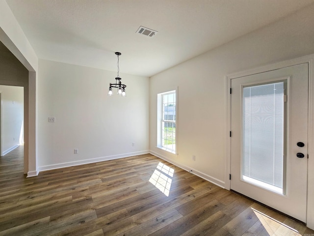 unfurnished dining area with a chandelier and dark hardwood / wood-style flooring