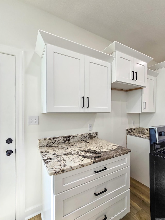 kitchen with white cabinets, dark hardwood / wood-style floors, and light stone counters