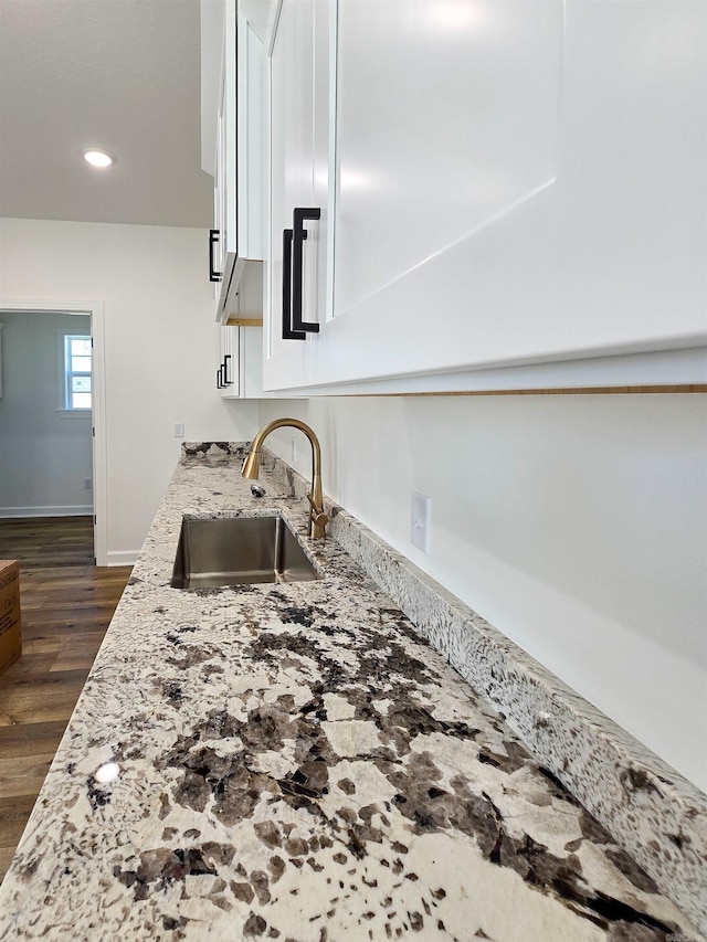 room details featuring light stone counters, sink, and dark hardwood / wood-style floors