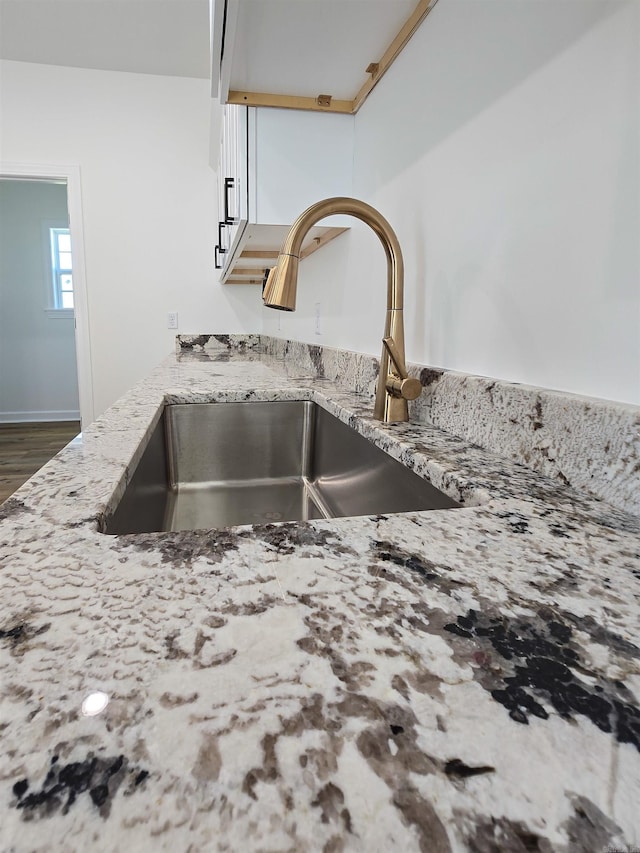 room details featuring light stone counters, dark wood-type flooring, and sink