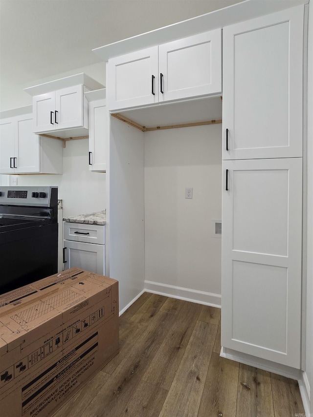 kitchen featuring light stone countertops, white cabinetry, black / electric stove, and dark wood-type flooring