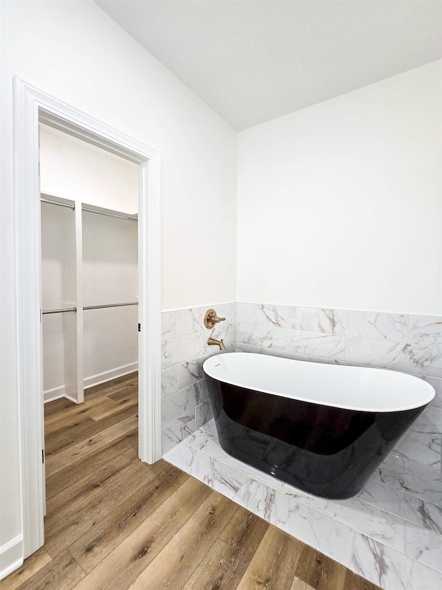 bathroom with wood-type flooring and a tub to relax in