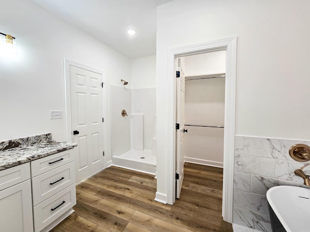 bathroom featuring hardwood / wood-style floors, vanity, separate shower and tub, and tile walls