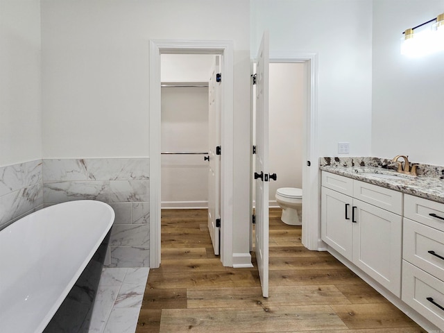 bathroom with toilet, a bathtub, vanity, and hardwood / wood-style flooring