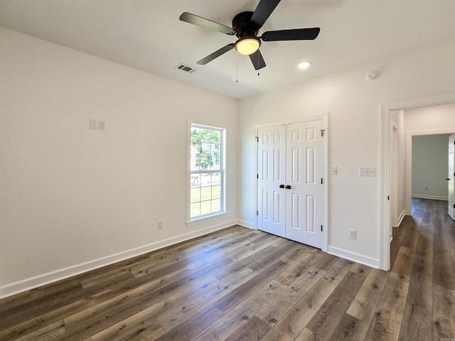 unfurnished bedroom with ceiling fan, a closet, and dark wood-type flooring