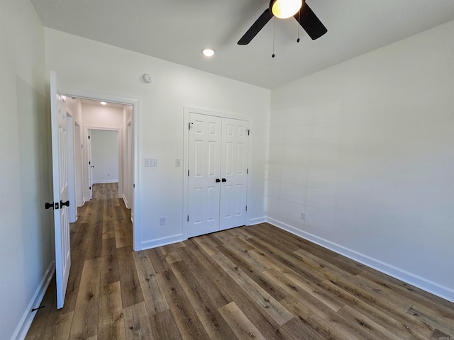 unfurnished bedroom featuring ceiling fan, a closet, and dark wood-type flooring